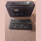 Černý kytarový procesor BOSS GT-1 v originální krabici. Na přístroji i na obalu jsou viditelné nápisy BOSS GT-1 GUITAR EFFECTS PROCESSOR a logo COSM.…