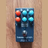 Tmavě modrý efekt pedál s nápisem bass synth. Na horní části jsou šestihranné ovladače v oranžové a tyrkysové barvě s popisky VOICE, CUTOFF, ENVELOPE…
