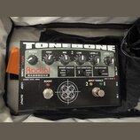 Černý kytarový efekt Radial BASSBONE z řady TONEBONE. Na horní straně jsou umístěny šest otáčivých ovladačů s popisky BOOST, HIGH, MID, LOW, LEVEL-2…