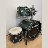 Sada bubnů v tmavě zelené barvě s chromovaným hardwarem. Na basovém bubnu je bílé logo SONOR a nápis DRUMCENTER.CZ, na ostatních bubnech jsou viditel…