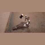 Kovový basový pedál v stříbrném provedení. Na stupni je viditelné logo SONOR a kruhový protiskluzový prvek. Mechanismus obsahuje řetězové tahlo a nas…