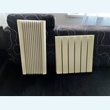 Dvě světlé akustické panely z pěny s žebrovaným povrchem. Panely mají obdélníkový tvar a jsou tvořeny svislými drážkami. Na fotografiích nejsou žádné…