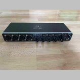Černý audio rozhraní s nápisem behringer na horní straně a označením U-PHORIA UMC404HD v levém horním rohu. Přední panel obsahuje čtyři kombinované v…