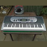 Šedý digitální klavír s bílými a černými klávesami. Na levé straně ovládacího panelu je nápis CASIO a na pravé straně TOUCH RESPONSE. V pravém dolním…