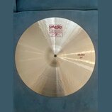 Kruhový činel z kovového materiálu s viditelným broušením. Na povrchu je červenobílé logo Paiste 2002 a nápisy TRADE MARK, MADE IN SWITZERLAND. V pra…
