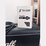 Bílý hranatý přístroj s nápisy Two notes AUDIO ENGINEERING a Torpedo Captor X. Dole jsou uvedeny funkce REACTIVE LOAD BOX, VIRTUAL CABINET, ATTENUATO…