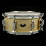 Zlatý buben s kovovými obručemi a ladidly. Uprostřed korpusu je oválný štítek s nápisy „Slingerland“, „QUALITY DRUMS“ a „CHICAGO, ILL. U.S.A.“. Povrc…