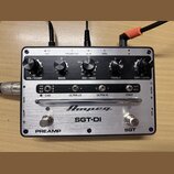 Stříbrný kytarový preamp s nápisem Ampeg a modelem SGT-DI. Zařízení má pět černých otočných ováčků s popisky VOL / COMP, BASS, MID / FREQ, TREBLE a G…