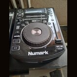 Černý DJ kontroler značky Numark s modelem NDX500. Zařízení obsahuje velký stříbrno-černý jogwheel, posuvník pitch bend a řadu tlačítek s nápisy jako…