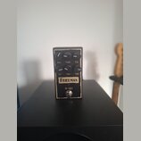 Kytarový efekt pedál v černém kovovém šasi s vypálenými okraji. Na přední straně jsou šest ovládacích knoflíků s popisky Bass, Treble, Pres, Vol, Gai…