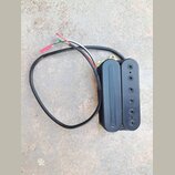 Černý humbucker s plastovým krytem a viditelnými póly na jedné z cívky. Snímač má připojený černý kabel, ze kterého vyvedeny červený, bílý a zelený v…