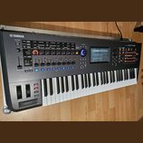 Černý digitální syntezátor s klávesnicí. Na levé straně horního panelu je logo a nápis YAMAHA, na pravé straně nápis MONTAGE. Přístroj obsahuje numer…
