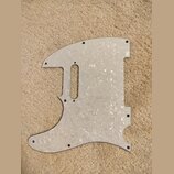 Bílá pickguard s perleťovým vzorem pro elektrickou kytaru. Je vyrobena z plastového materiálu a obsahuje výřezy pro snímače a ovládací prvky. Povrch…