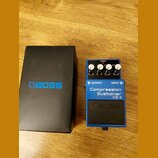 Modrý kytarový efekt pedál značky BOSS s nápisem Compression Sustainer CS-3. Na horní straně jsou tři ovládací knoflíky s popisky MIN MAX, LO HI a MI…