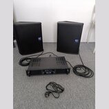 Dva černé reproduktory s mřížkami a modrými logy „dB Technologies“. Mezi nimi je umístěn černý rackový zesilovač s nápisem „skytec PRO244“ a „AMPLIFI…