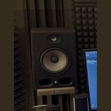 Černý studiový monitor s jedním vysokofrekvenčním a jedním nízkofrekvenčním reproduktorem. Reproduktor je umístěn na stojanu s nápisem th-mann. V dol…