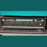 Čelní panel kytarového zesilovače s nápisy acoustic a MODEL 114. Na pravé straně je nalepený štítek s textem SERVAAS' MUZIEKHANDEL B.V. a logem M. Pa…