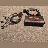 Černý napájecí adaptér Voodoo Lab PEDAL POWER 4x4 s nápisy HIGH CURRENT a ISOLATED DC OUTPUTS. K zařízení patří napájecí kabel do zásuvky a sada čern…