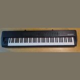 Černá klaviatura s bílými a černými klávesami. Na pravé straně je bílý nápis M-AUDIO a pod ním menší text HAMMER 88 PRO. Horní panel obsahuje řadu tl…