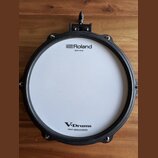Elektronický buben s bílým pleteným povrchem a černým obručováním. Na horní části je nápis Roland MESH HEAD a v dolní části V-Drums s doplňkem Patent…
