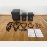 Sada černých studiových monitorů tvořená dvěma menšími reproduktory a jedním větším subwooferem. Na všech třech jednotkách je viditelné logo PreSonus…