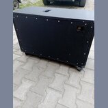 Černý obdélníkový reproduktorový box s povrchem z textilie. Na zadní straně je umístěn jeden konektor pro kabel a v horní části horního panelu je výř…