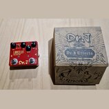 Červený kytarový efekt s nápisy LANCELOT DISTORTION a Dr. J. Na horní straně jsou tři černé otočné knoflíky s popisy DIST BOOST, TONE a GAIN. Na spod…