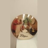 Zlatavý kovový činel s viditelným broušením. Na povrchu jsou nápisy A, CUSTOM a v dolní části logo Avedis Zildjian. V centru je čitelně napsáno CRASH…