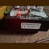 Černý efekt pedál s bílým nápisem Data Corrupter a logem EarthQuakerDevices. Na horní straně jsou bílé ovládací knoflíky, přepínač a svítící červená…