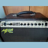 Kytarový kombozesilovač v hnědém vinylovém potahu s černou textilní maskou. Na ovládacím panelu jsou nápisy MEGATONE a Acoustic AC30R, vlevo dole je…