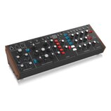 Černý analogový syntetizátor v dřevěném rámu. Na panelu jsou viditelné nápisy OSCILLATOR BANK, MIXER, MODIFIERS, CONTROLLERS a OUTPUT. Přístroj obsah…