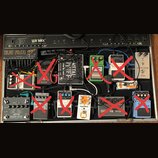 Fotografie znázorňuje efektový pedalboard v černém kufru značky Warwick. Na desce je umístěno několik kytarových efektů, včetně značek Joyo (model PR…