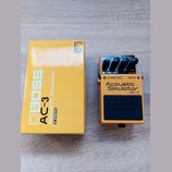 Žlutý efekt pedál Boss Acoustic Simulator AC-3 v originální žluté krabici. Na pedálu jsou tři ovládací knoflíky, červená kontrolka s nápisem CHECK a…