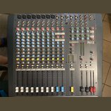 Šedý mixovací pult s vícevstupovými kanály a posuvníky. Na horní části je vidět nápis ALLEN&HEATH a označení modelu PA12. Zařízení obsahuje řadu bare…
