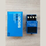 Modrý kompresor značky BOSS, model Compression Sustainer CS-3. Pedál má čtyři ovládací knoflíky s popisky LEVEL, TONE, ATTACK a SUSTAIN, červenou kon…
