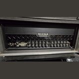 Kytarový zesilovač s černým povrchem a chromovanými detaily. Na předním panelu je logo MESA ENGINEERING a nápis Dual Rectifier ROADSTER. Přístroj obs…