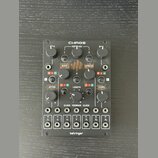 Černý modul s nápisem CHAOS v horní části a behringer ve spodní. Zařízení obsahuje několik otočných potenciometrů, tlačítka a v dolní části 12 zapušt…