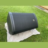 Černý stage monitor s kovovou mřížkou v přední části. Na pravé straně mřížky je umístěn malý stříbrný obdélníkový štítek s logem a nápisem ALTUS. Pov…