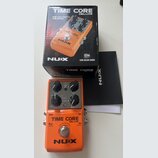 Oranžový efekt pedál s nápisy TIME CORE DELUXE a NUX. Na horní části jsou čtyři černé ovládací knoflíky s popisky Tap/T Lock/Normal, Mix, Time a Repe…