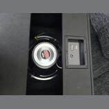 Fotografie zachicuje vnitřek černé reproduktorové skříně. Uvnitř je vidět reproduktor s bílým středem a červeným logem s nápisem CELESTION a číslem 1…