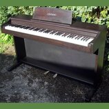 Digitální piano v tmavě hnědé dřevěné provedení s černým spodním panelem. Na horním stojáku na noty je bílý nápis CELVIANO a vpravo nad klávesami je…