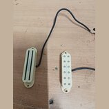 Dvě elektrické snímače v krémovém provedení s plastovými kryty. Levý snímač je typu humbucker s nápisem "Seymour Duncan". Pravý snímač je typu single…