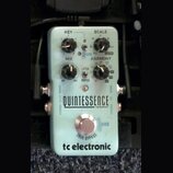 Světle modrý efekt pedál s nápisy QUINTESSENCE HARMONY a tc electronic. Na horní části jsou tři černé otočné ovladače s popisky KEY, SCALE a MIX, dál…