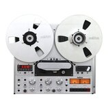 Stříbrný cívkový magnetofon s dvěma velkými bílými cívkami, na kterých je nápis REVOX. Přístroj má digitální displej s červeným číslem -0.03.50 a v d…