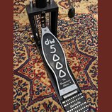Černý bicí pedál s kovovými prvky. Na šlapadle je bílým nápisem značka dw a model 5000, dále text The Drummer's Choice.® a logo dw na horní části kon…