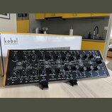Černý analogový semi-modulární syntetizátor s nápisem kobol EXPANDER. Přední panel obsahuje zahlreiche ovládací knofíky, přepínače a zapojovací konek…