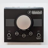 Černý monitor kontroler s velkým stříbrným volitkem uprostřed. Na horní části je nápis BIG KNOB PASSIVE MONITOR CONTROLLER a logo s postavou. Pod vol…