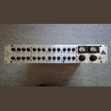 Stříbrný rackový procesor s nápisem TUBE ULTRA-G. Přední panel obsahuje dvě řady černých otočných ovířků s popisy jako FREQUENCY, BANDWIDTH a LEVEL.…