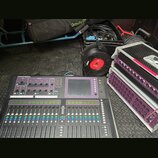 Digitální mixovací pult s nápisem ALLEN&HEATH GLD-80, vybavený faderem, tlačítky a displejem. Vedle pultu jsou dva rackové stageboxy s fialovými pane…