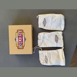 Kartonová krabice s barevným logem, ve kterém je nápis „Genuine American ANTIQUITY GUITAR PICKUPS“. Vedle krabice jsou tři bílé látkové sáčky se stah…